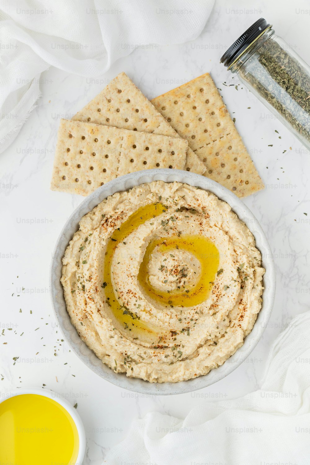 un bol de houmous avec des craquelins et de la moutarde