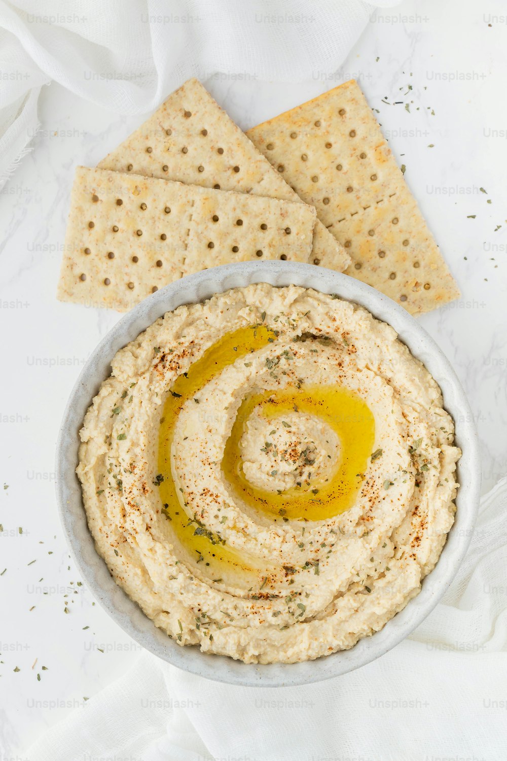 a bowl of hummus with crackers on the side