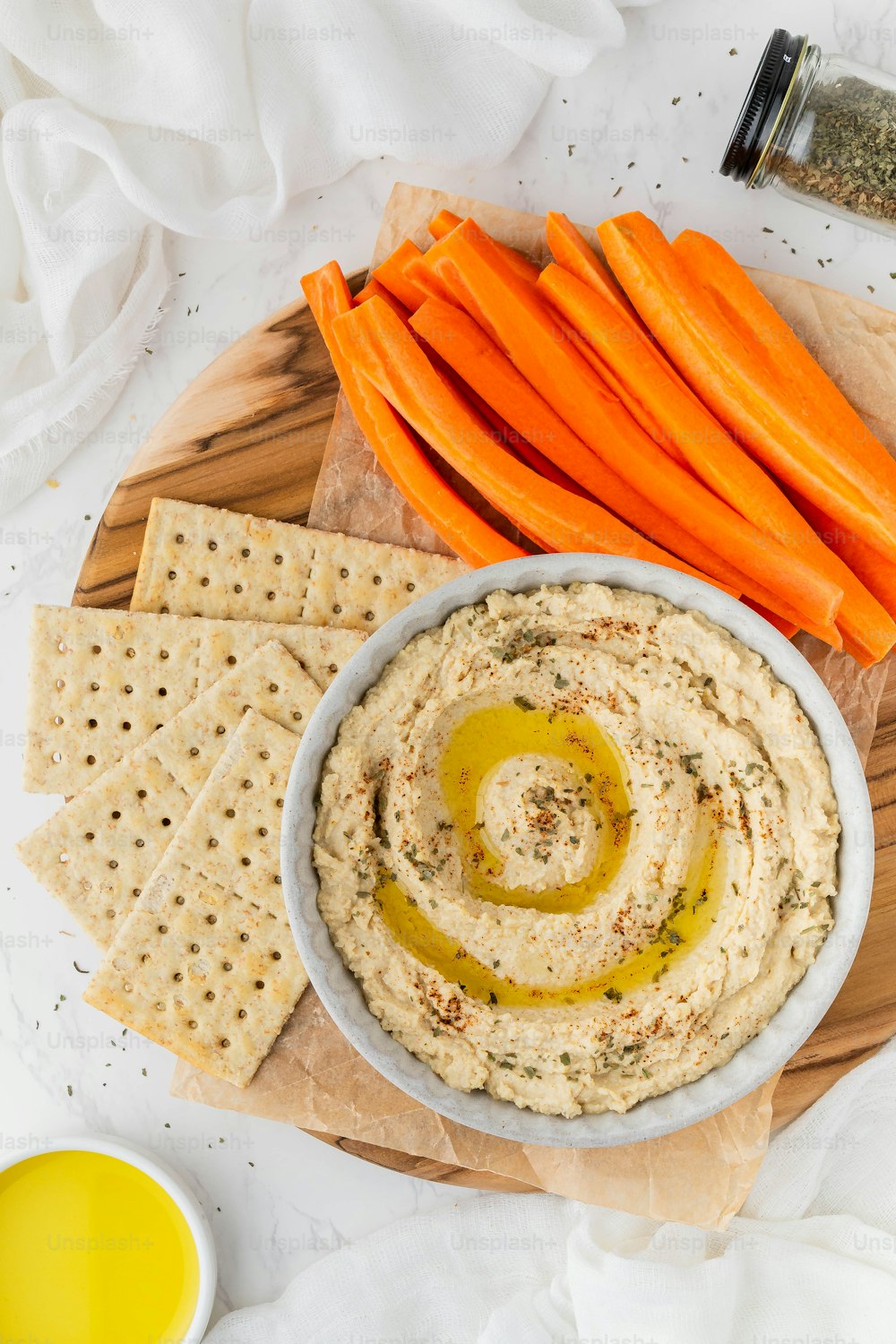 a bowl of hummus with carrots and crackers