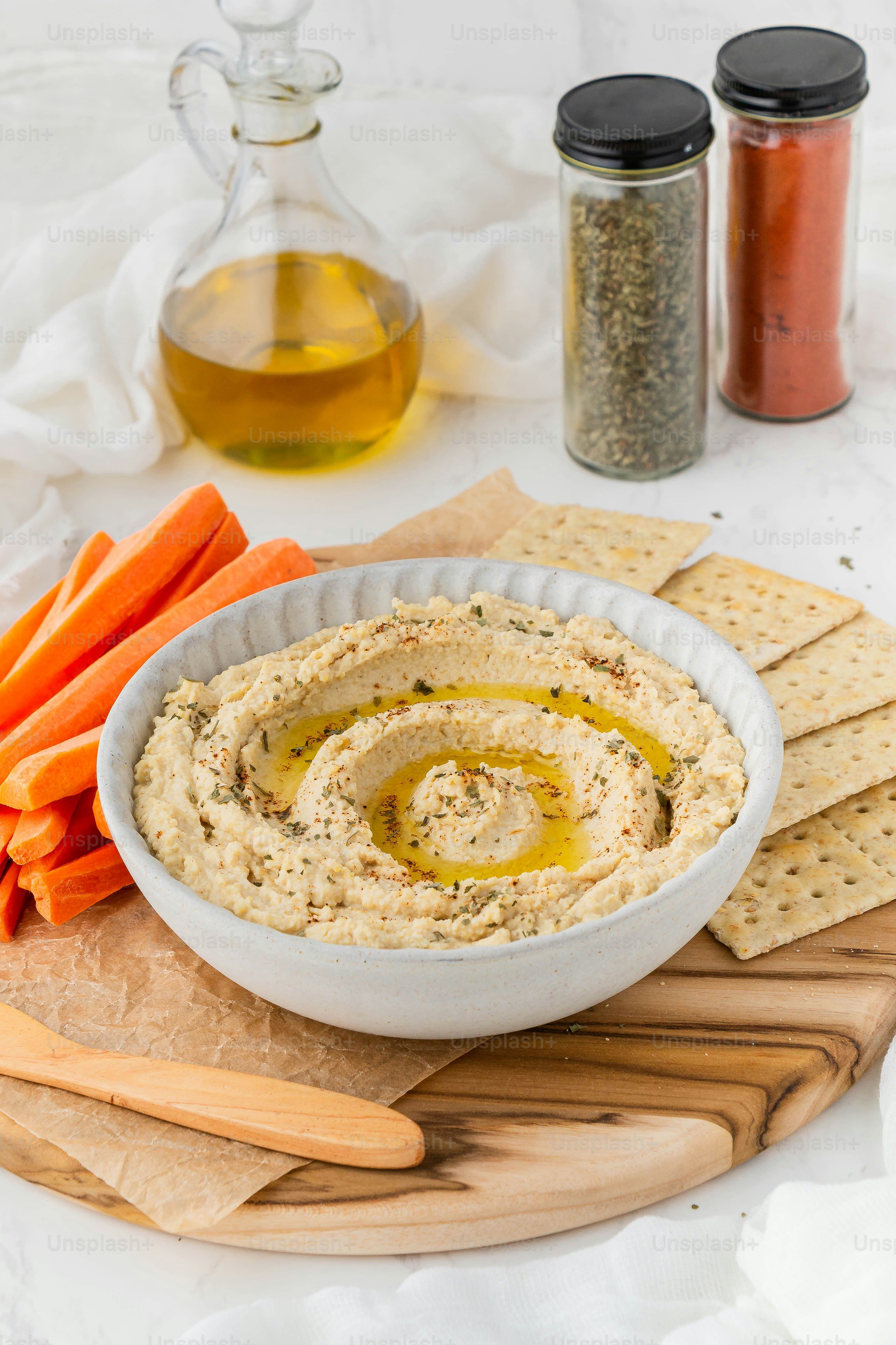 a bowl of hummus with carrots and crackers