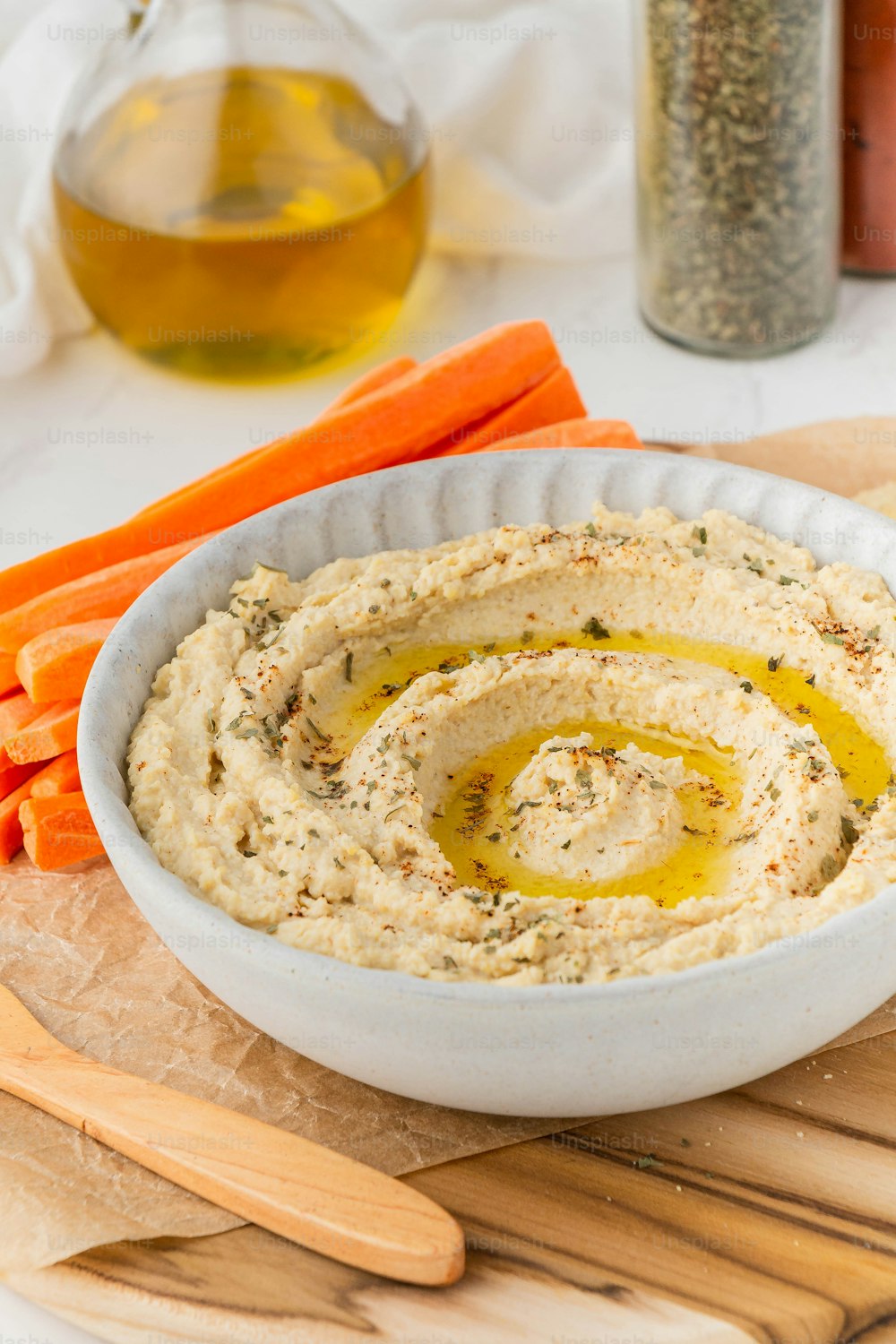 a bowl of hummus and carrots on a cutting board