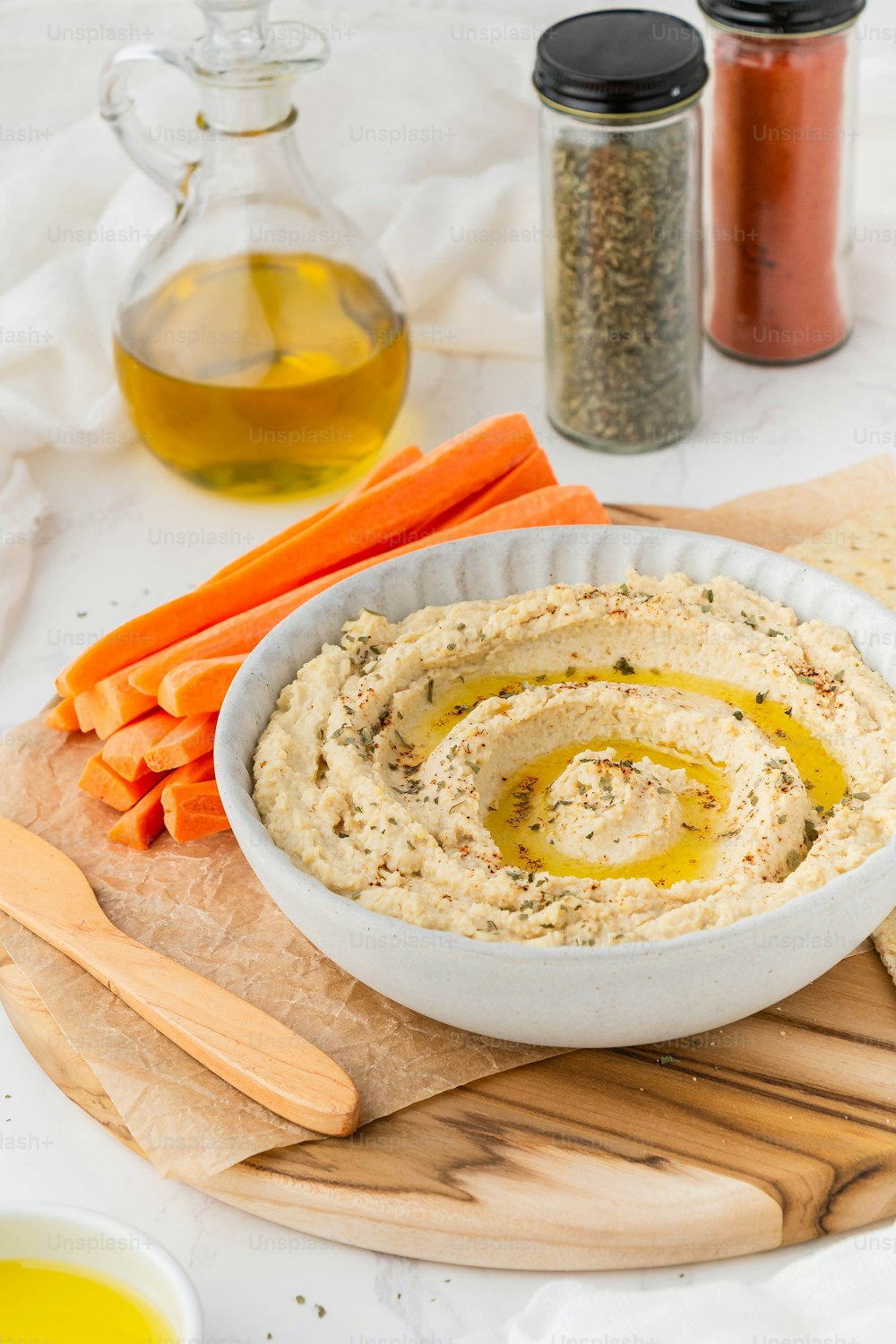 a bowl of hummus and carrots on a cutting board