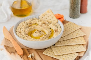 a bowl of hummus and crackers on a cutting board