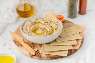 a bowl of hummus and crackers on a cutting board