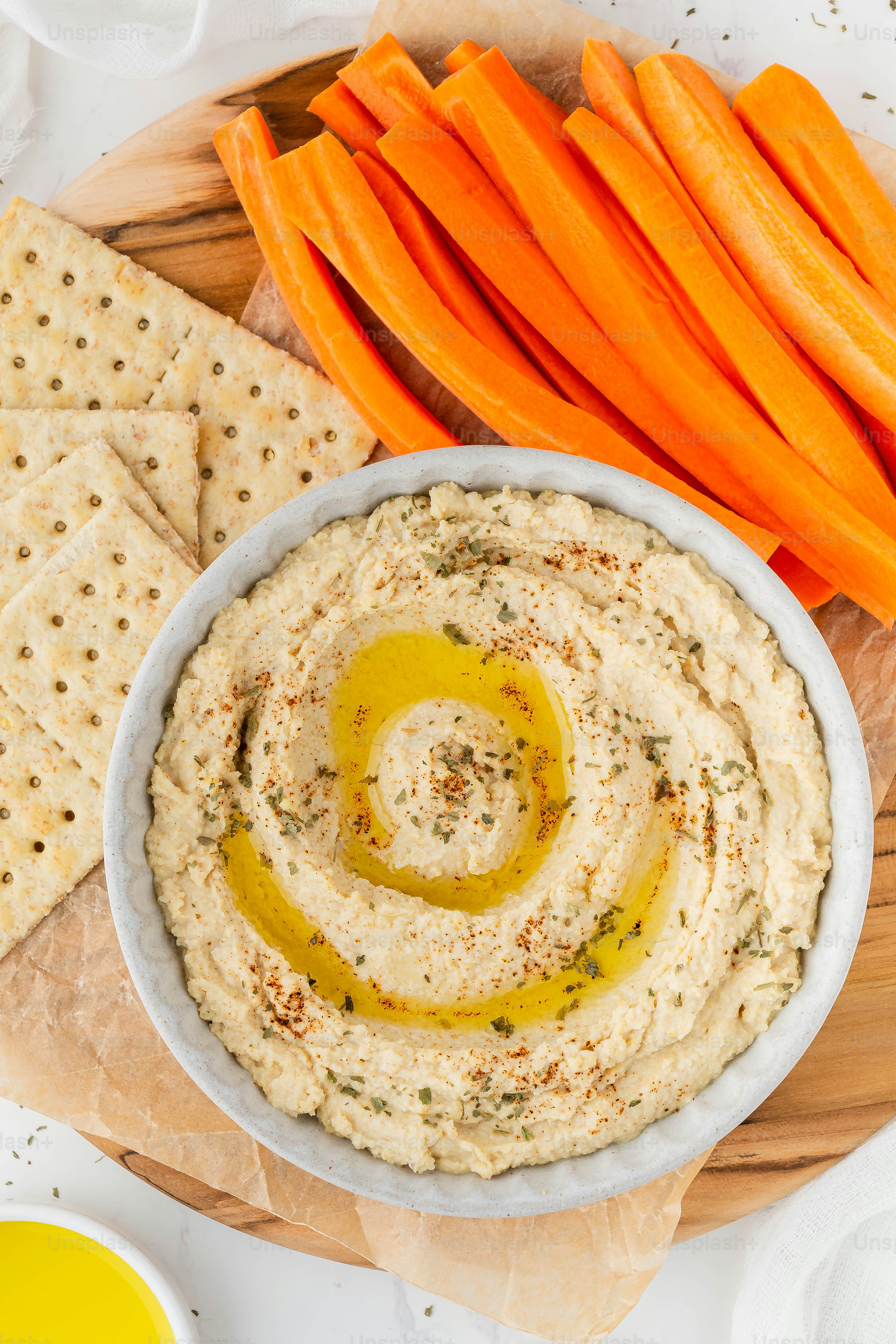 un bol de houmous avec des carottes et des craquelins