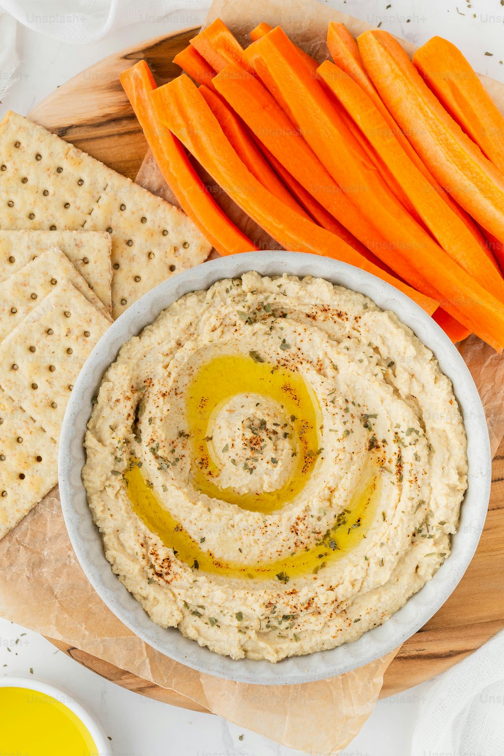 a bowl of hummus with carrots and crackers