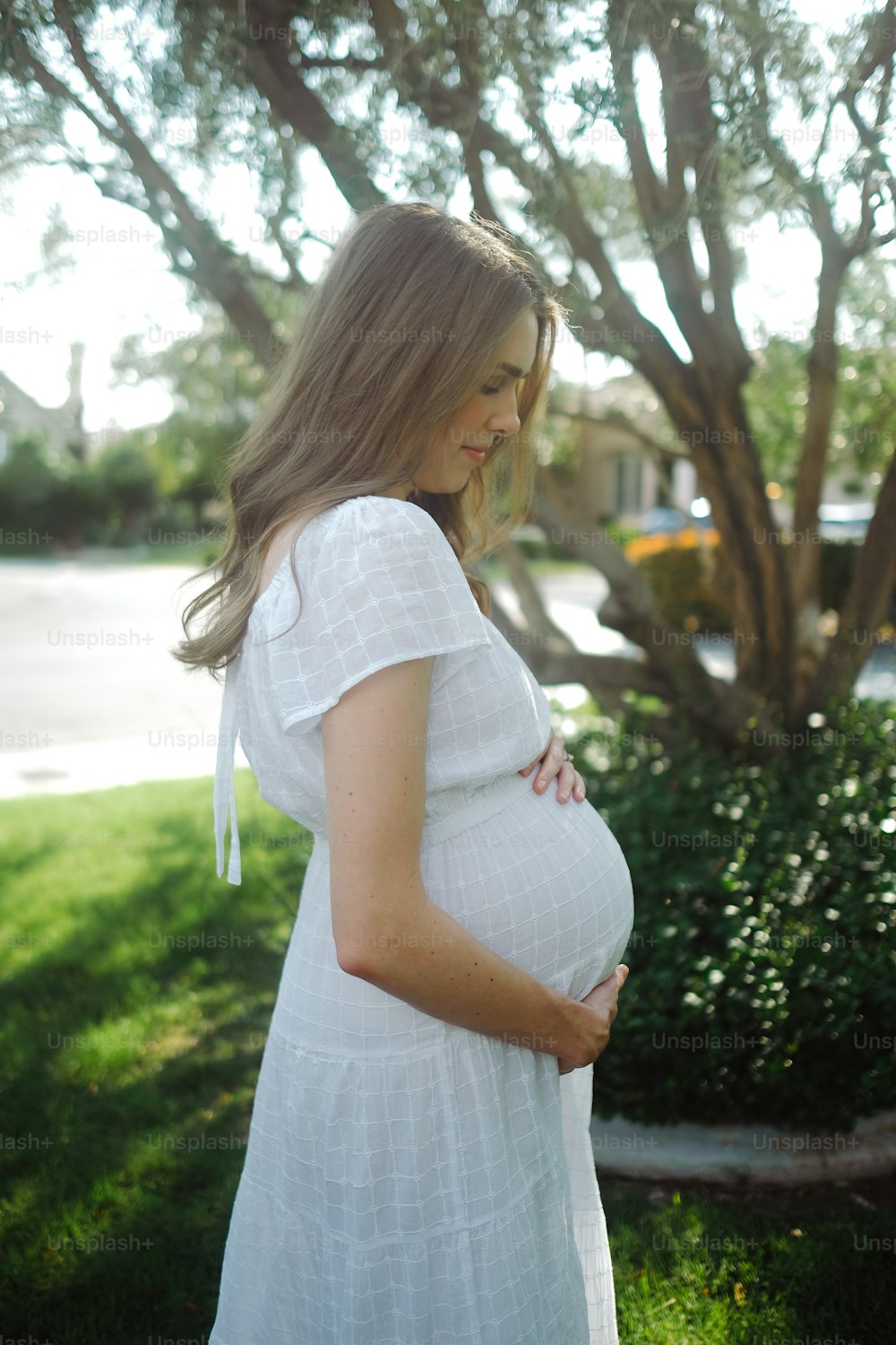 a pregnant woman standing in front of a tree