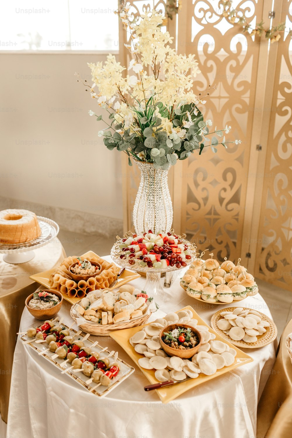 Una mesa cubierta con mucha comida junto a un jarrón de flores
