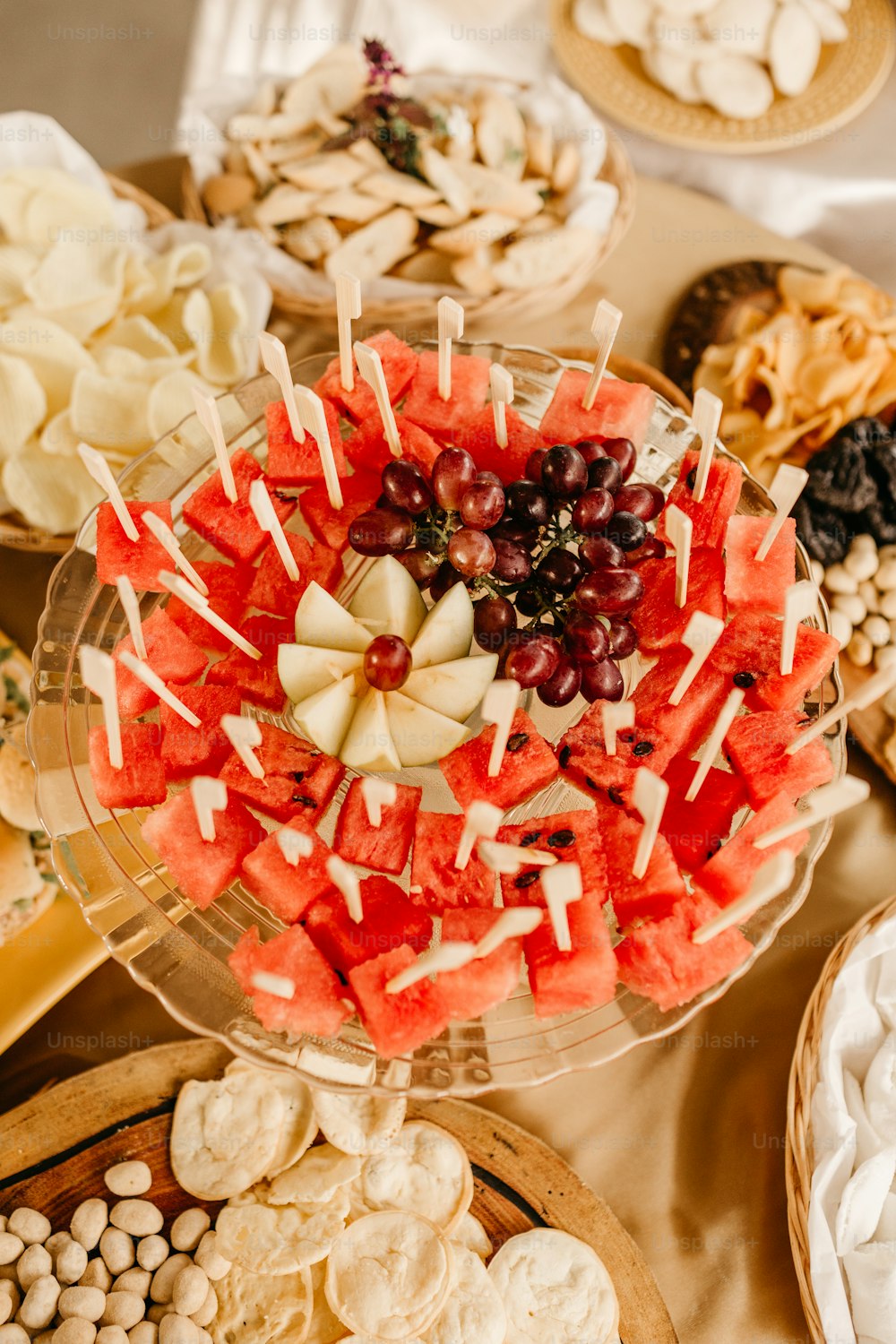 a platter of watermelon, grapes, cheese, and crackers