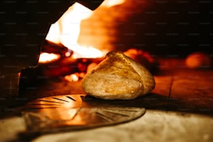 a loaf of bread sitting on a table in front of a fire