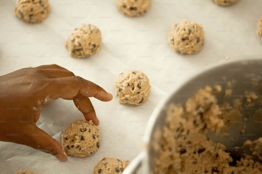 une main tendant la main vers un biscuit sur une plaque à pâtisserie