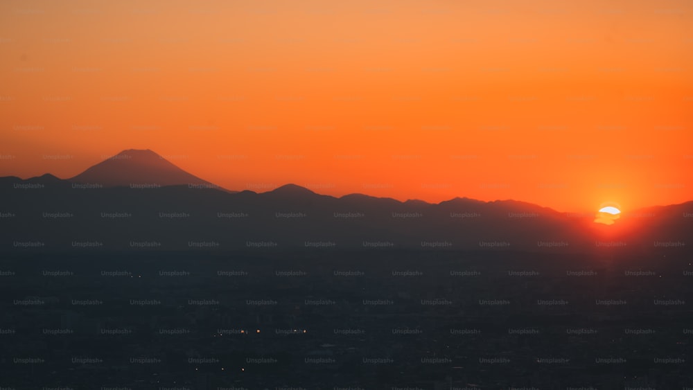 the sun is setting over a mountain range