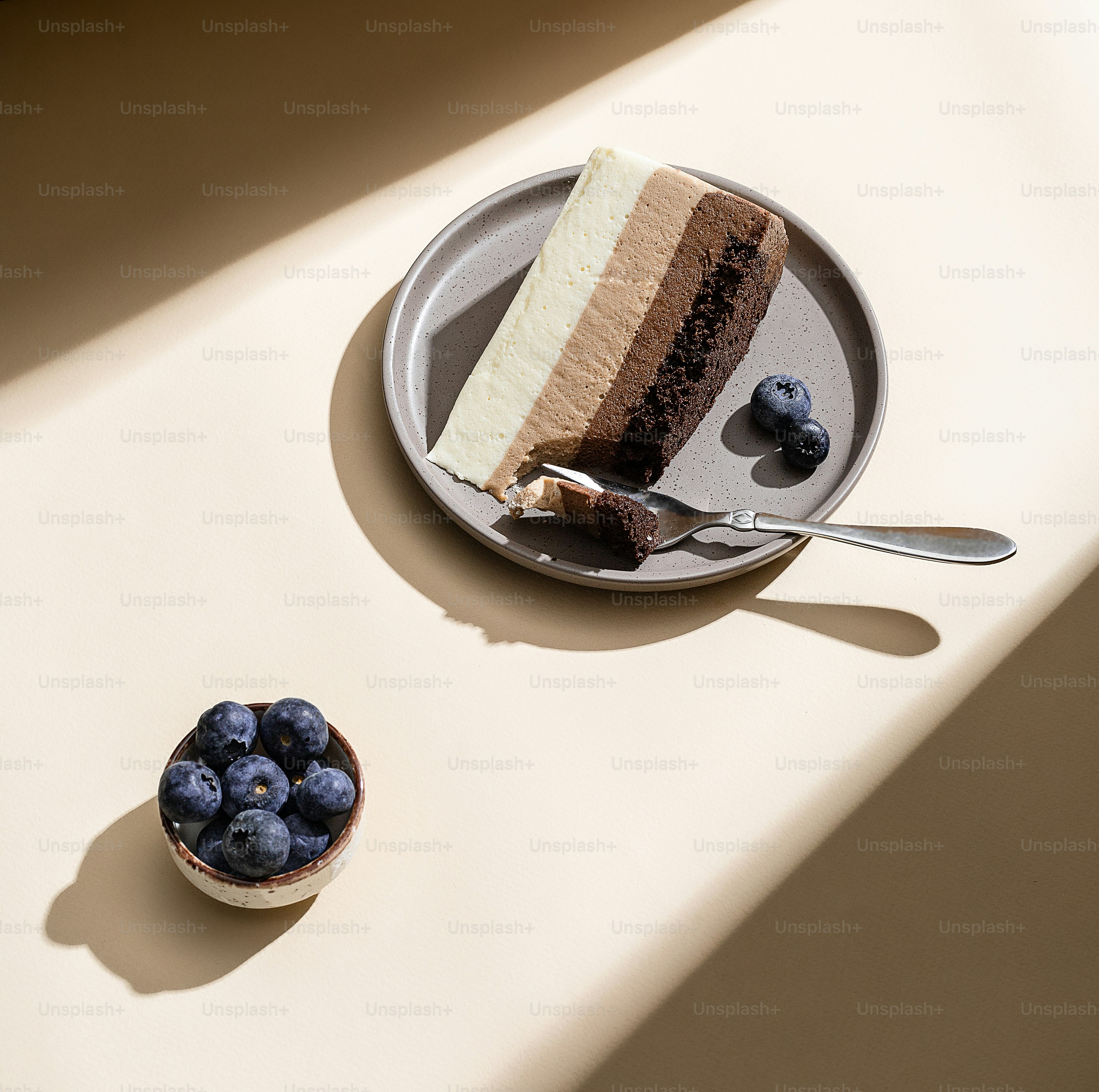 a piece of cake on a plate next to a bowl of blueberries