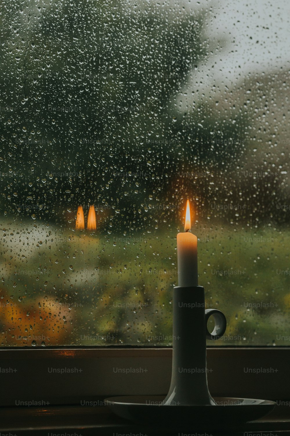 una candela seduta sopra un tavolo accanto a una finestra