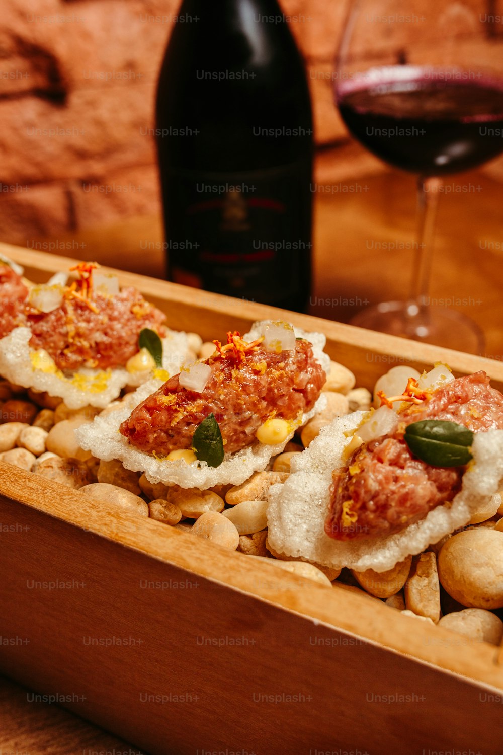 a wooden box filled with food next to a glass of wine