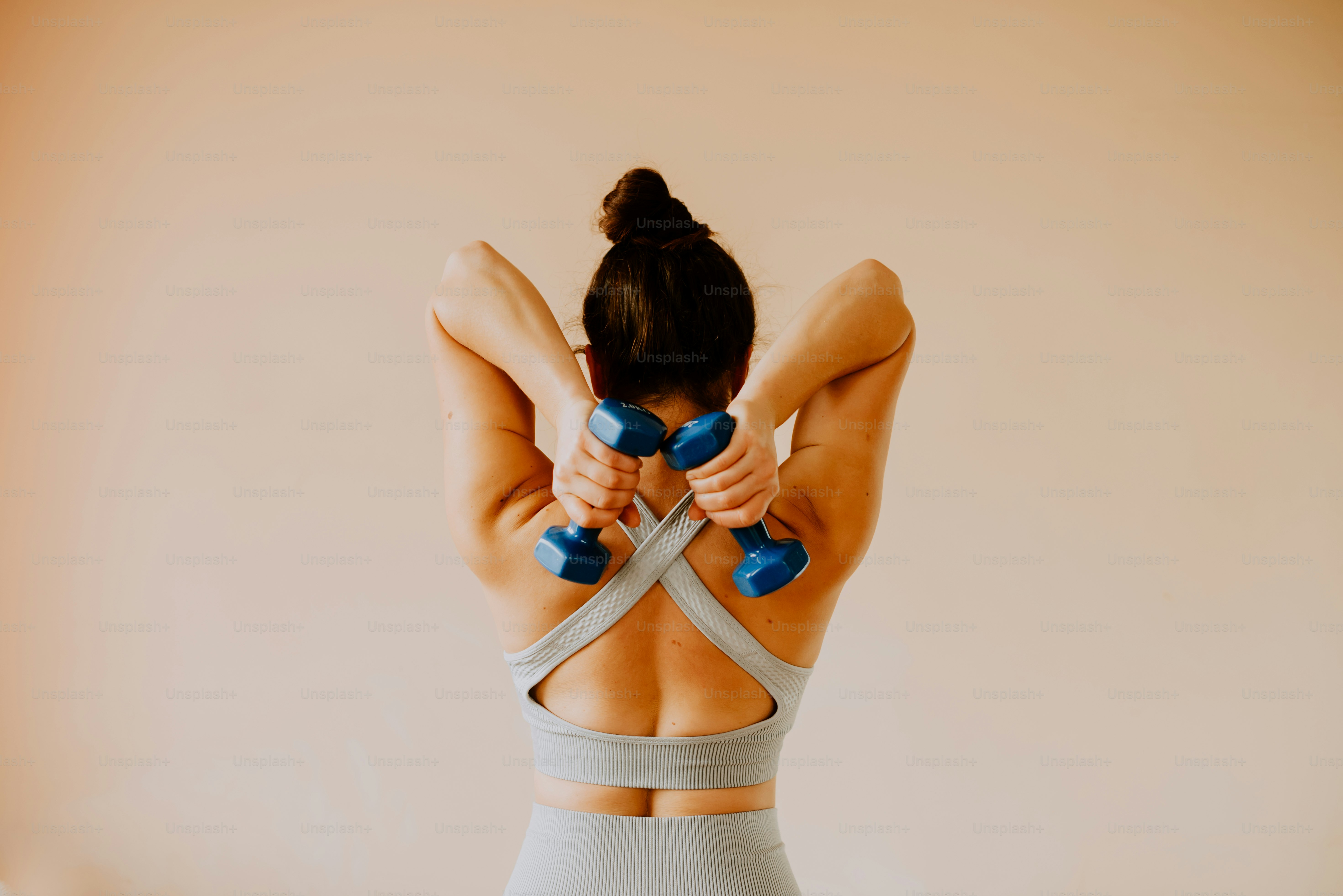 a woman doing exercises with dumbs on her back