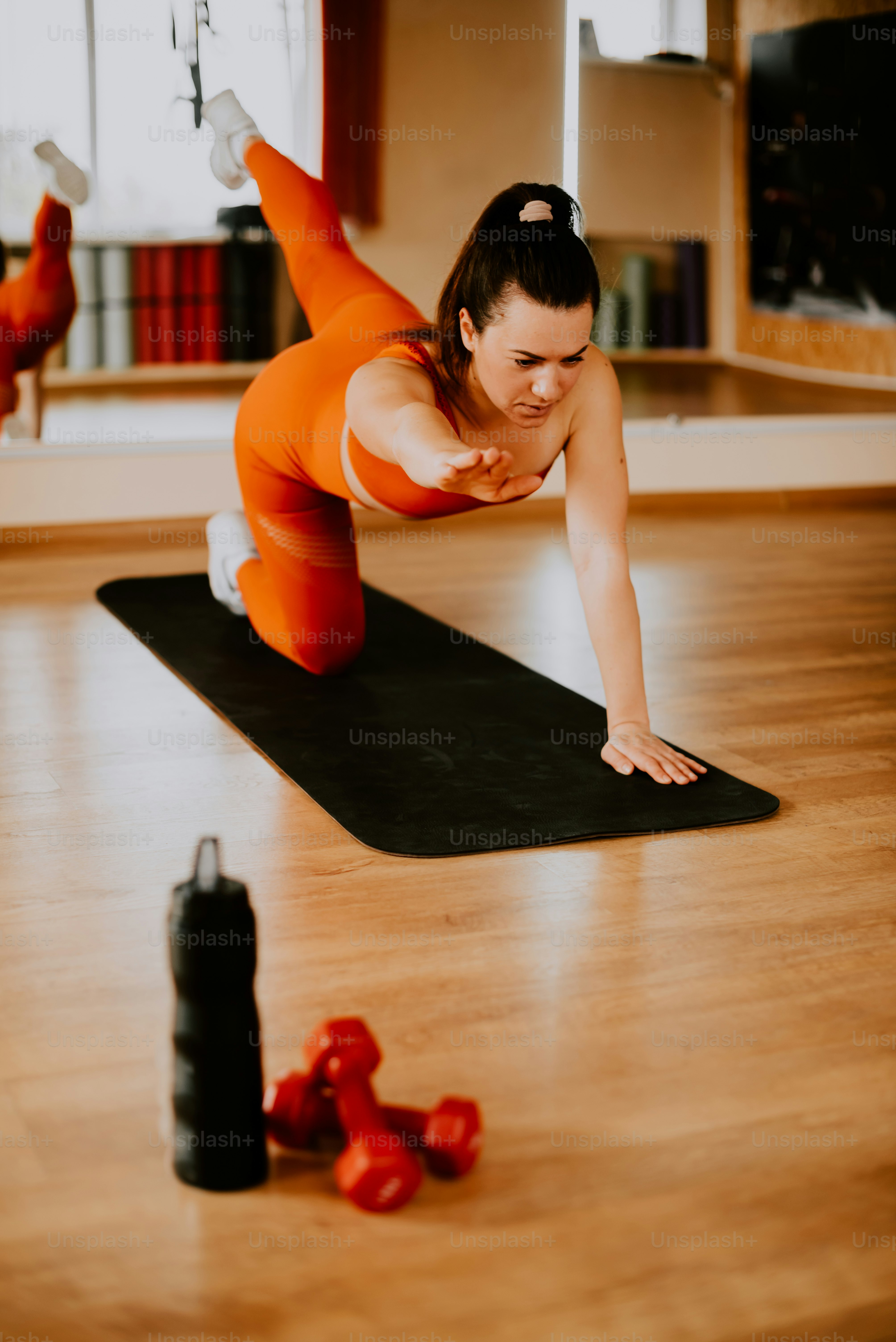 Une femme en tenue orange fait un exercice de planche