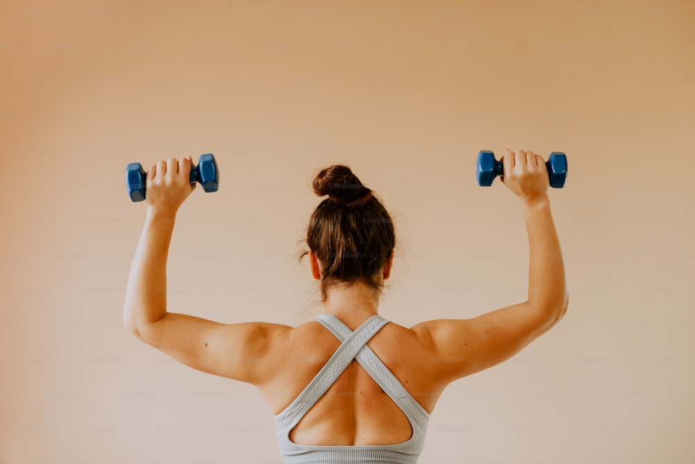 a woman is doing exercises with dumbbells
