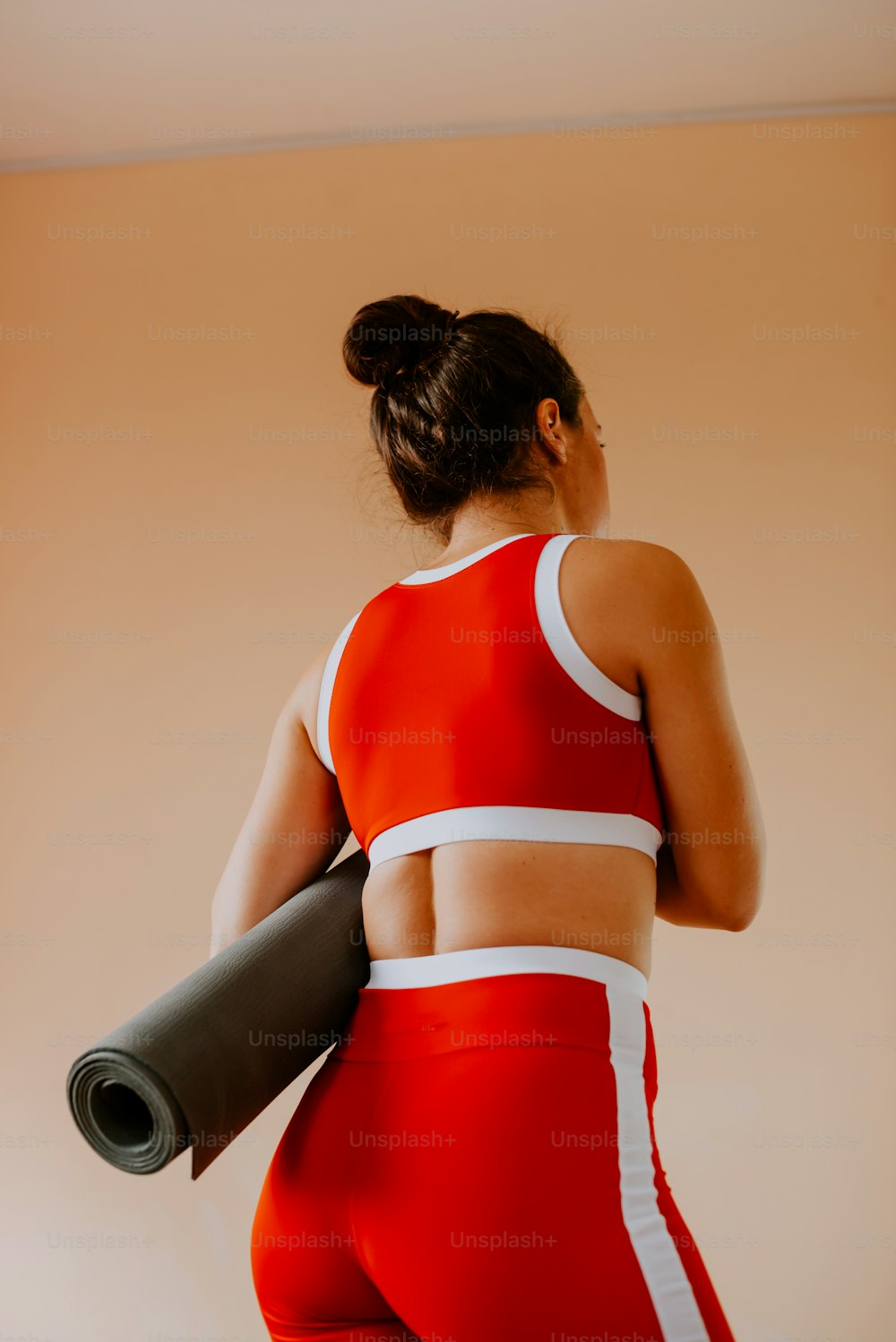 a woman in a red sports suit holding a yoga mat