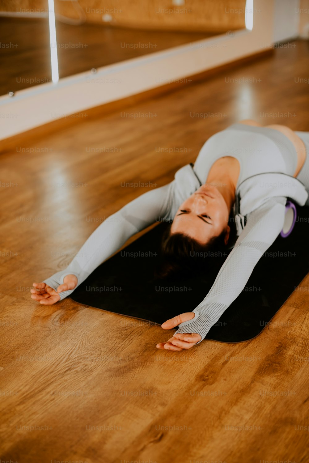a woman laying on a yoga mat in a room