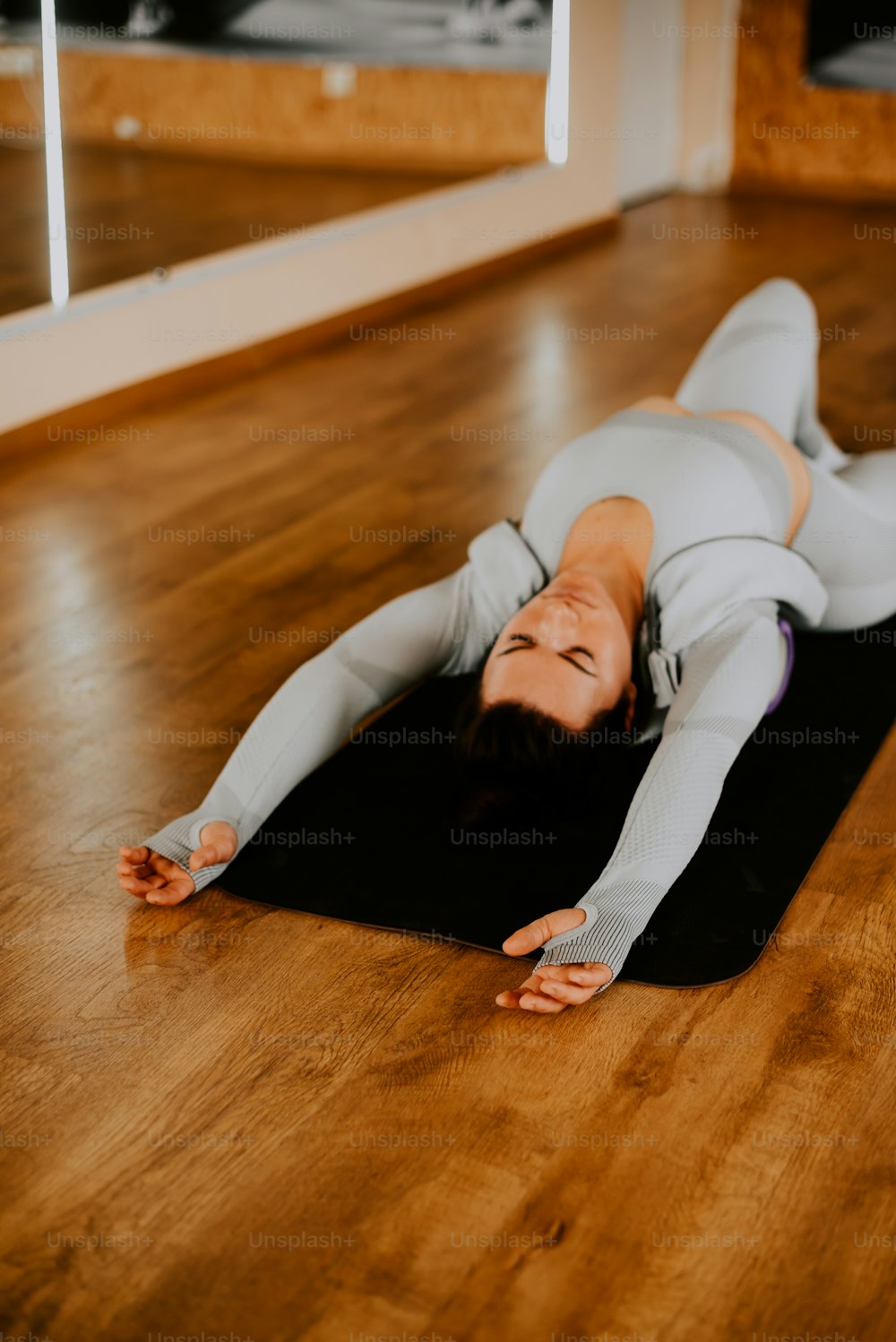 uma mulher deitada em um tapete de ioga em um quarto