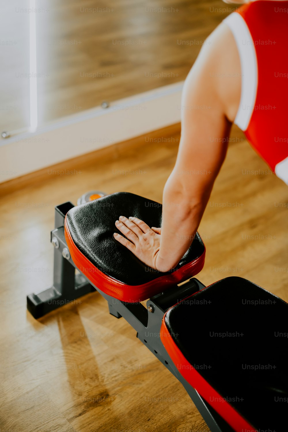 a woman in a red and white top is on a rowing machine