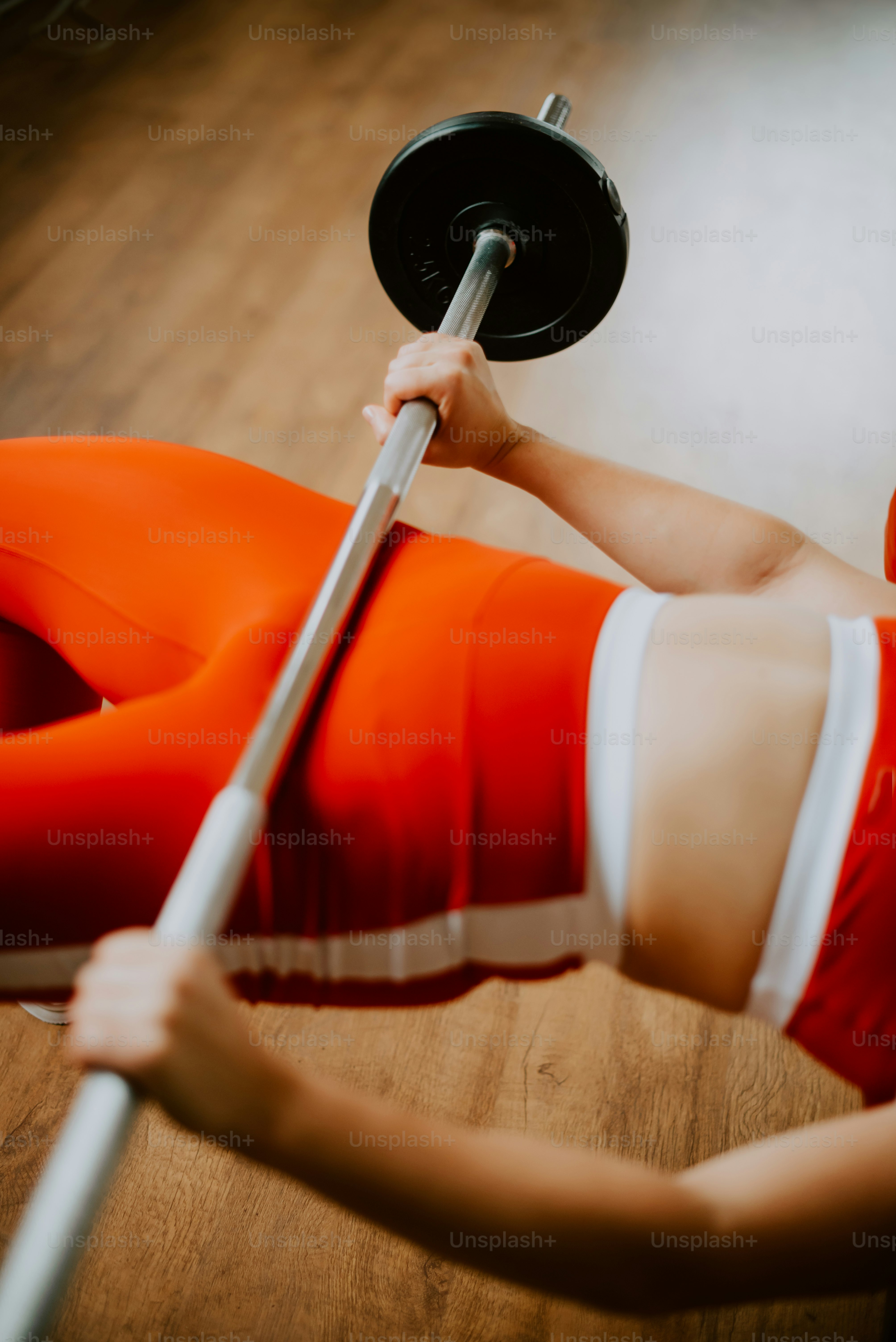 a woman in an orange outfit is doing exercises with a bar