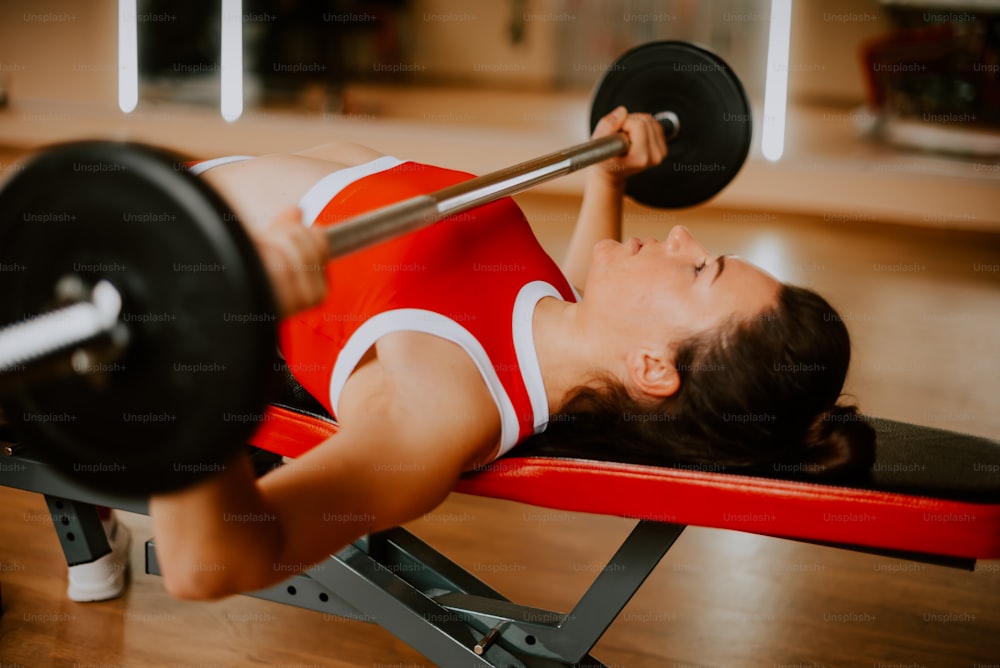 a woman laying on a bench with a barbell