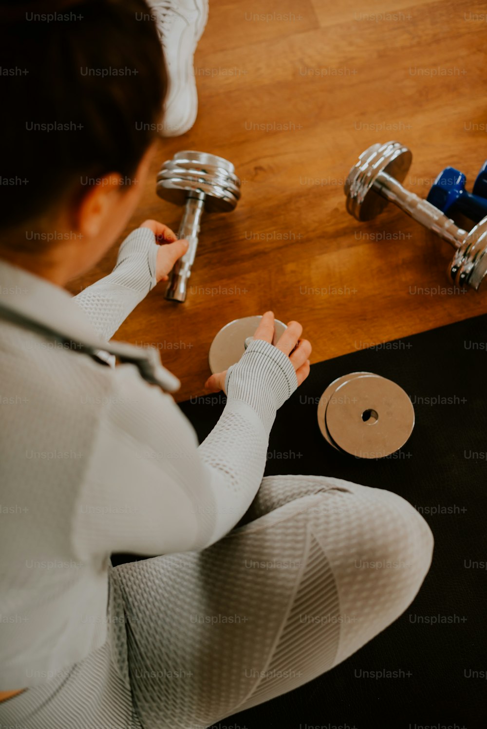 a woman sitting on the floor holding a pair of dumbbells