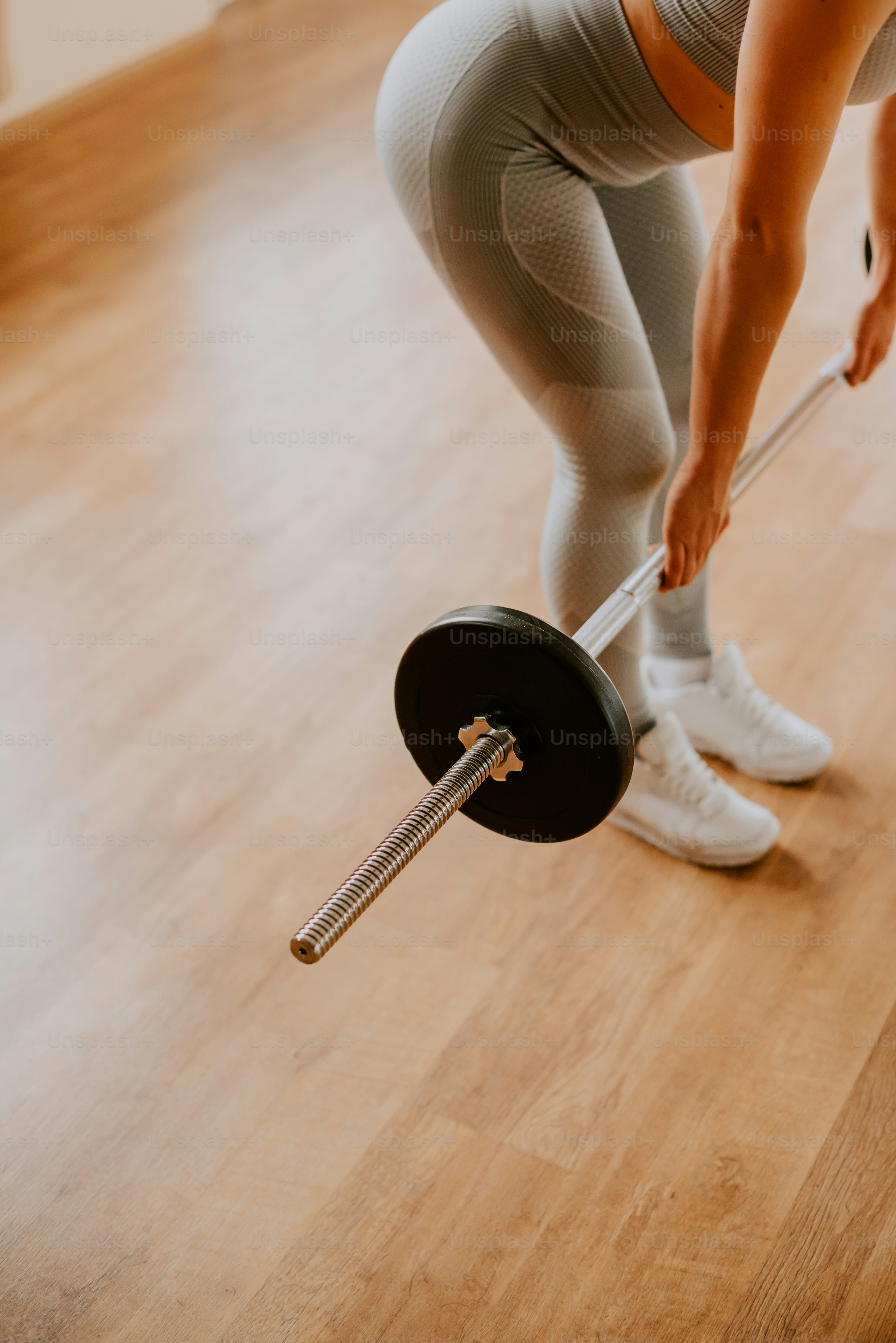 A woman in tights lifting a barbell on a hard wood floor photo Gym