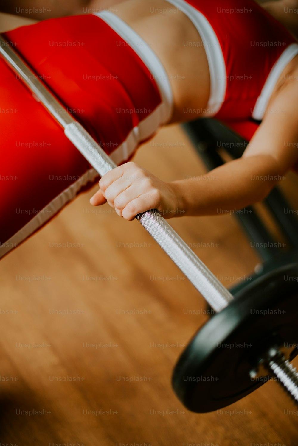 a woman in a red and white outfit is holding a barbell