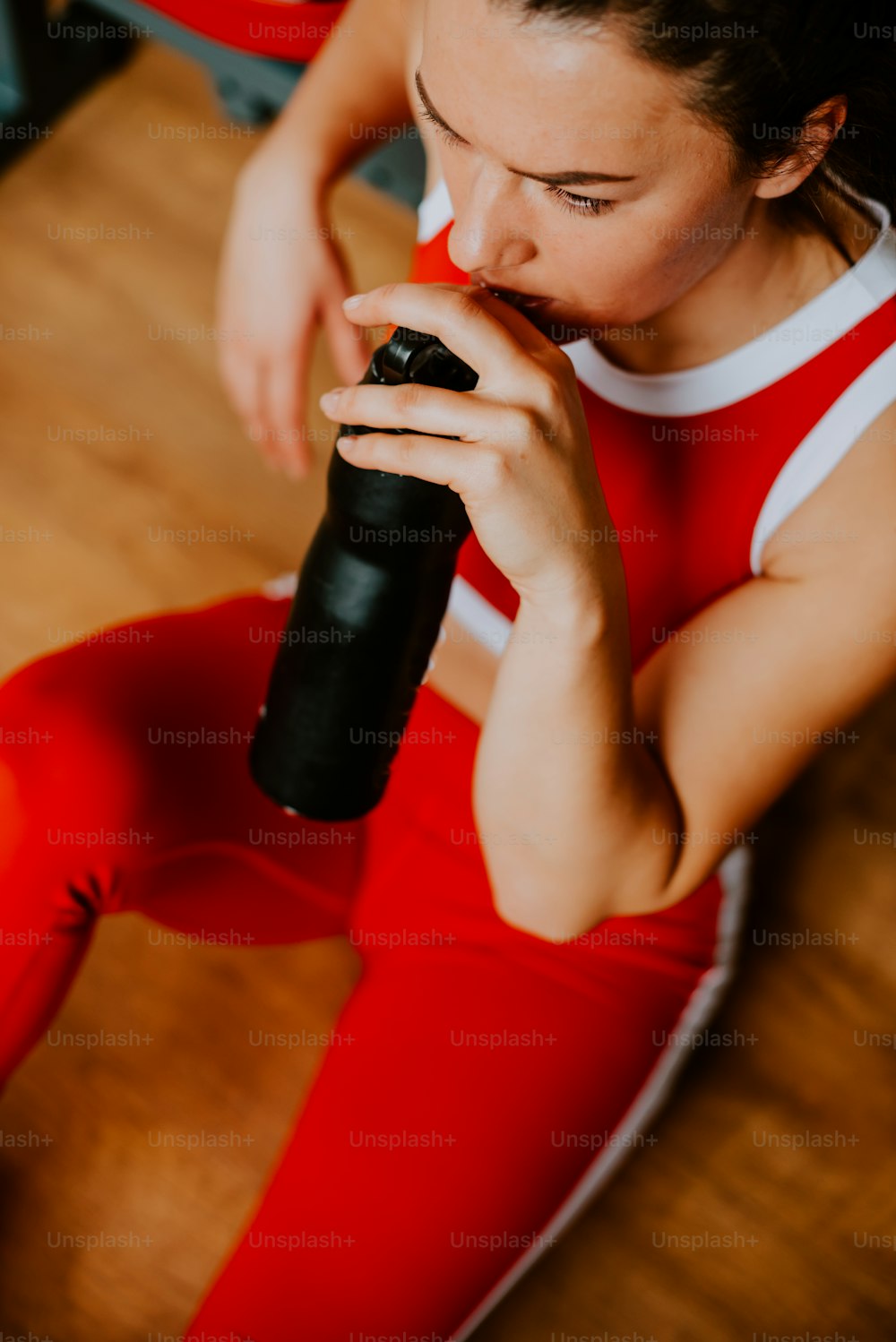 a woman sitting on the floor drinking from a bottle