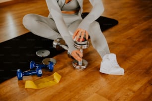 a woman sitting on the floor with a dumbbell
