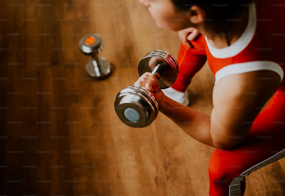 a woman in a red outfit is holding a dumbbell