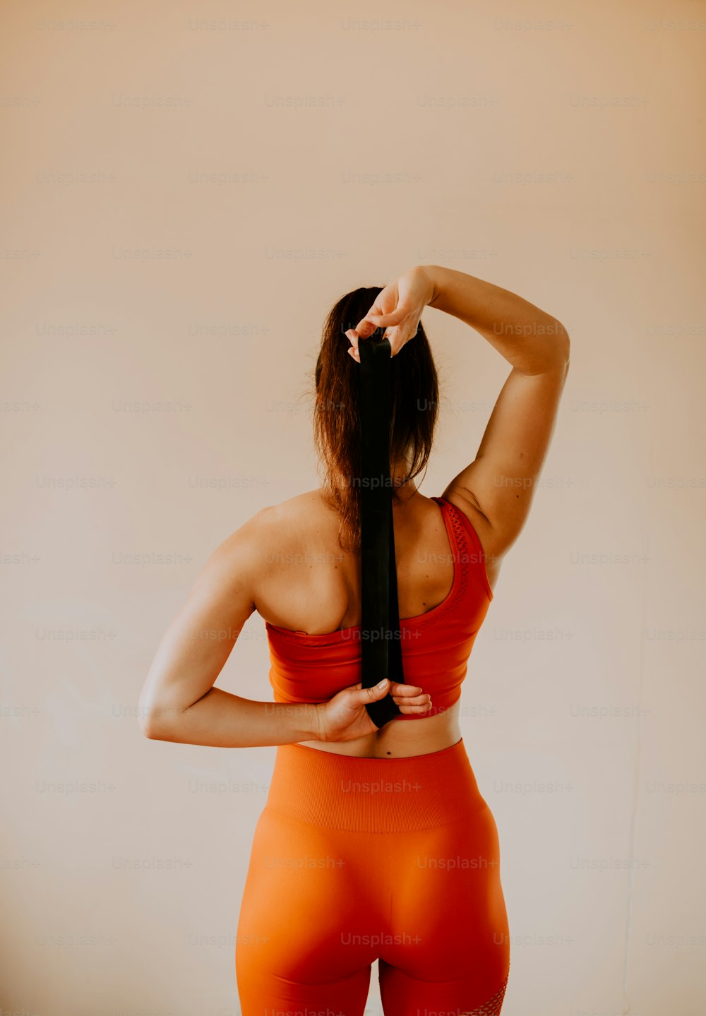 a woman in an orange sports bra is holding a black tie
