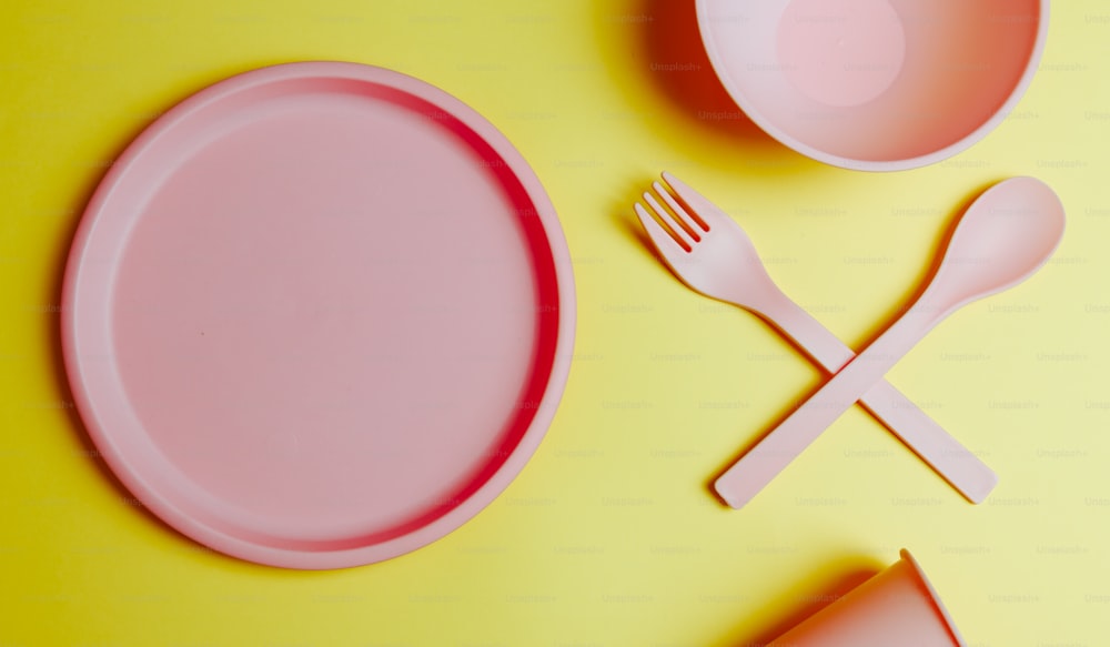 a pink plate with a fork and knife next to a pink plate