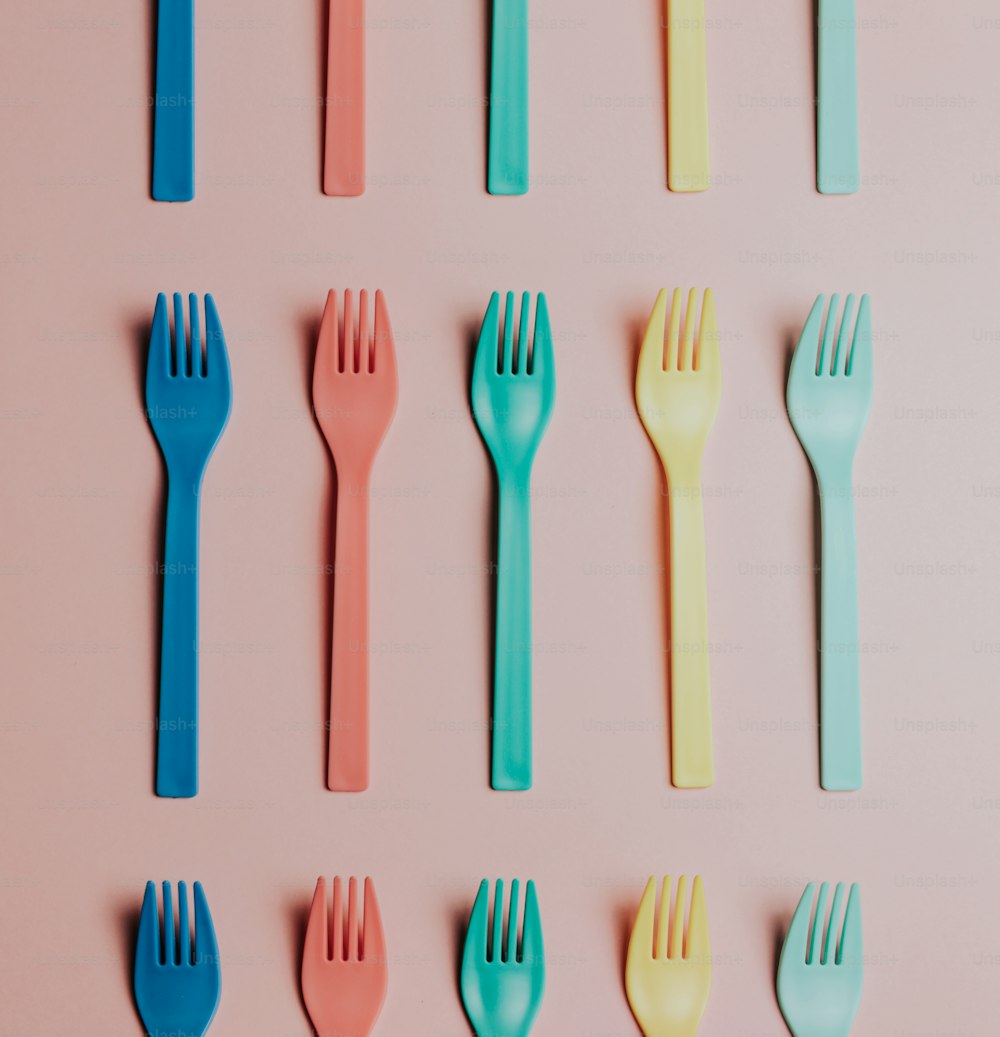 un gruppo di forchette e cucchiai di plastica su una superficie rosa