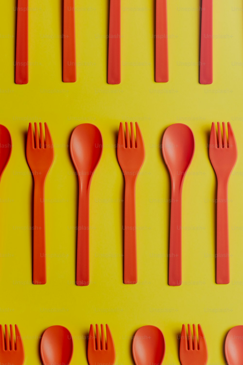 a group of red forks and spoons on a yellow background