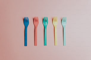 four forks lined up in a row on a pink surface