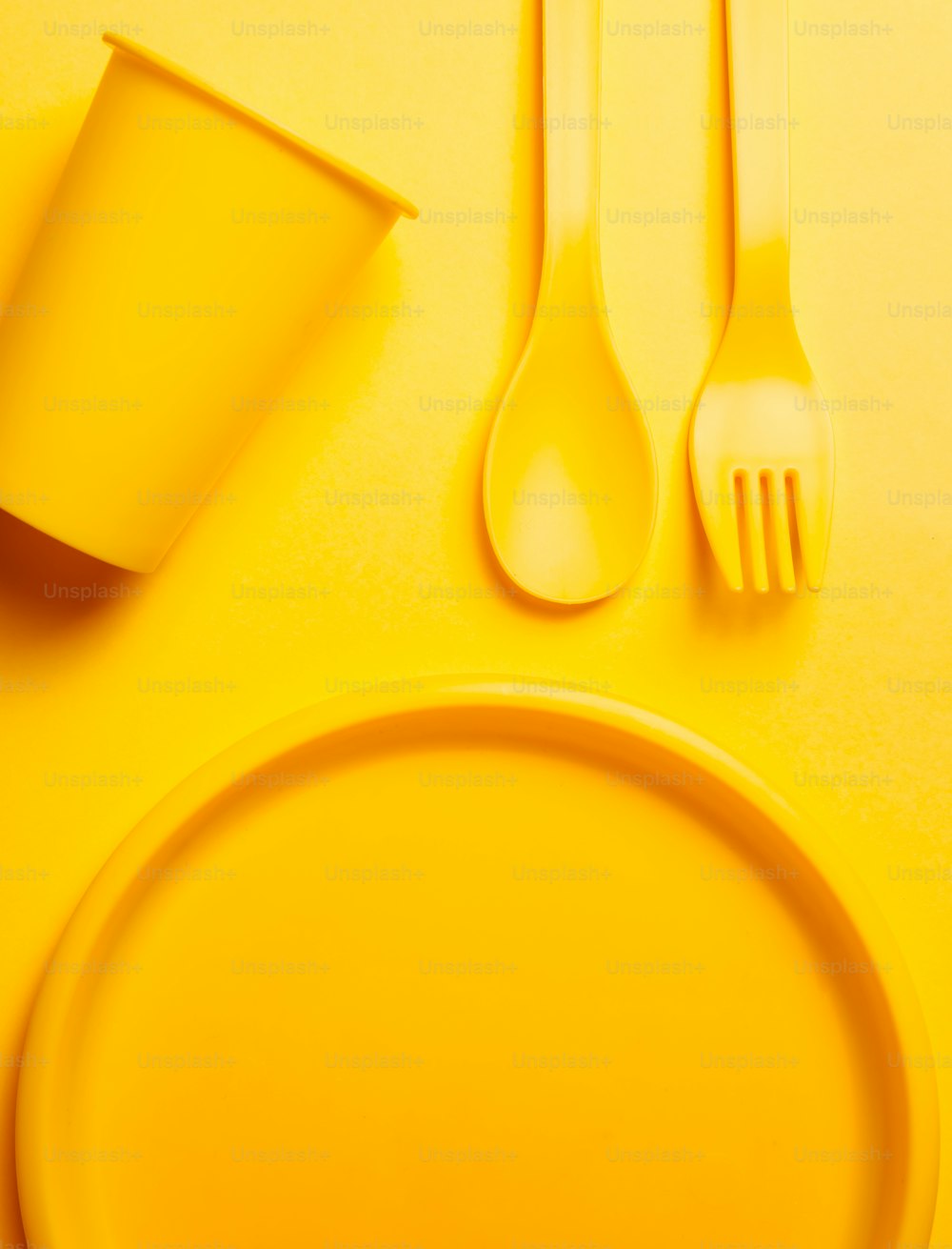a yellow table setting with utensils and a cup