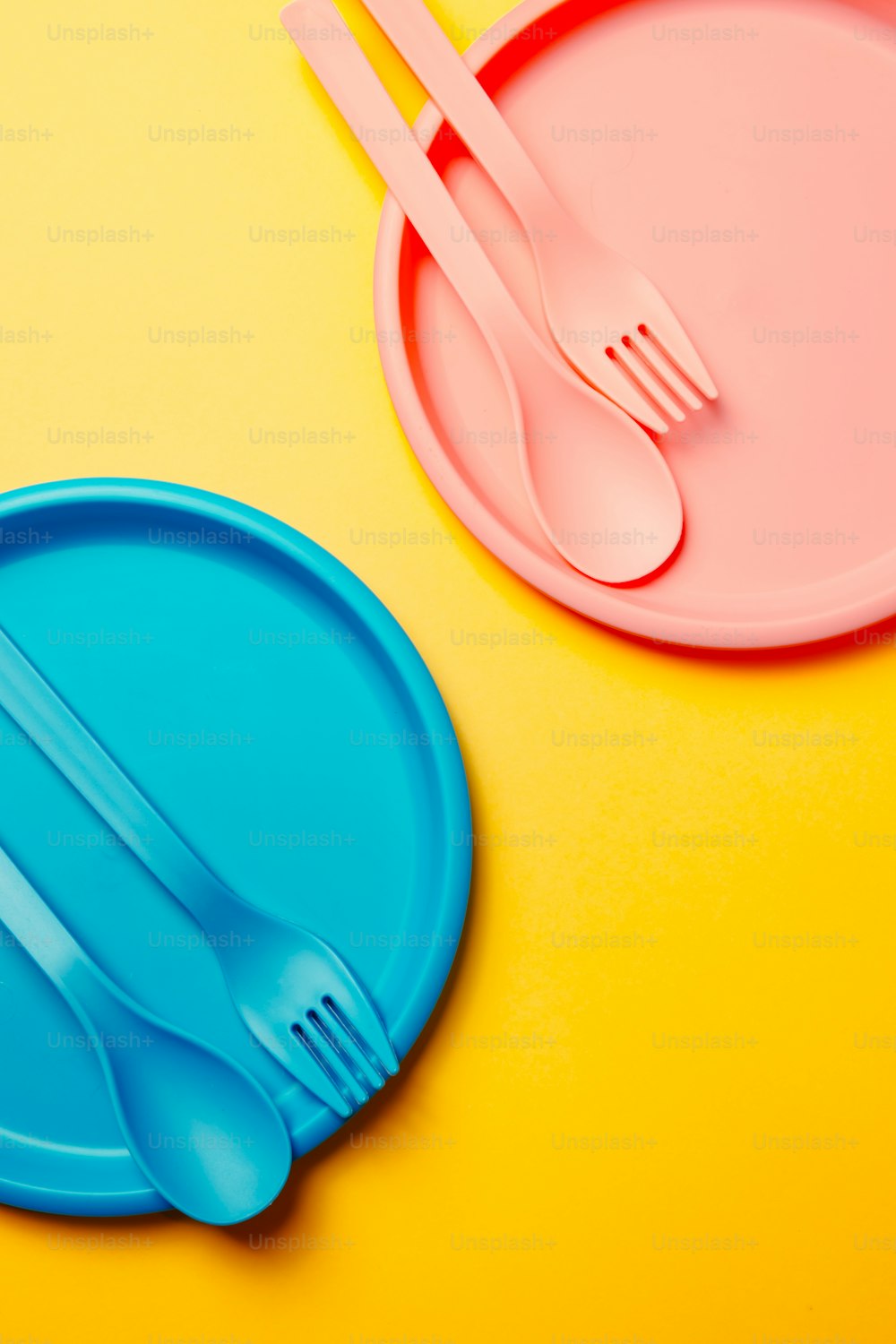 une fourchette en plastique et une assiette en plastique sur fond jaune et rose