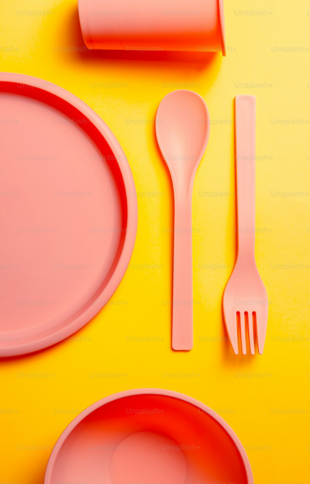 a yellow table topped with pink plates and utensils