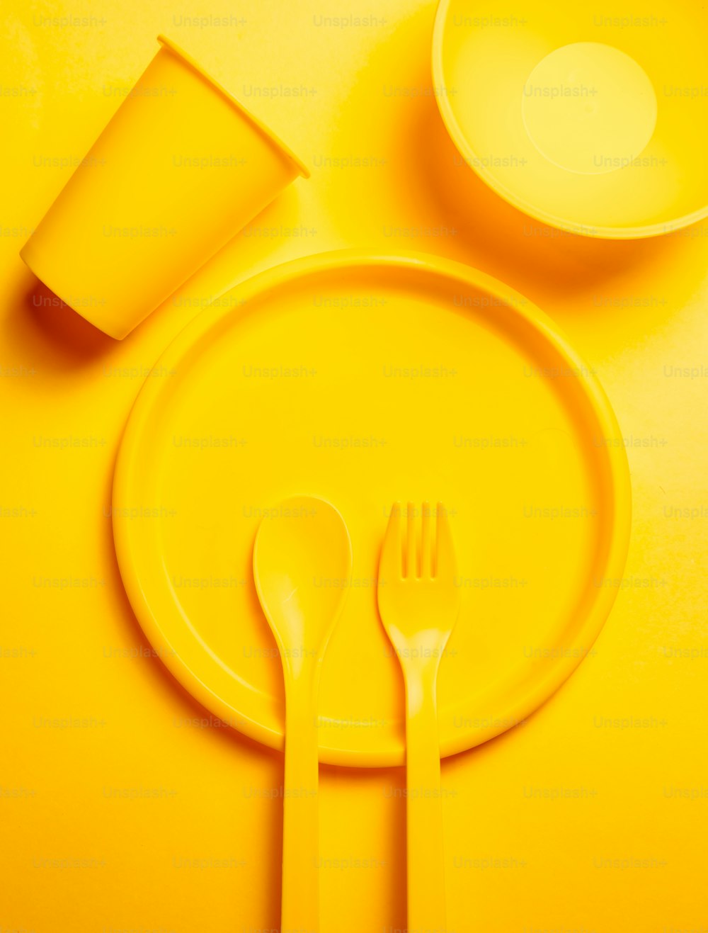 ein gelber Teller mit einer Gabel und einer Tasse darauf