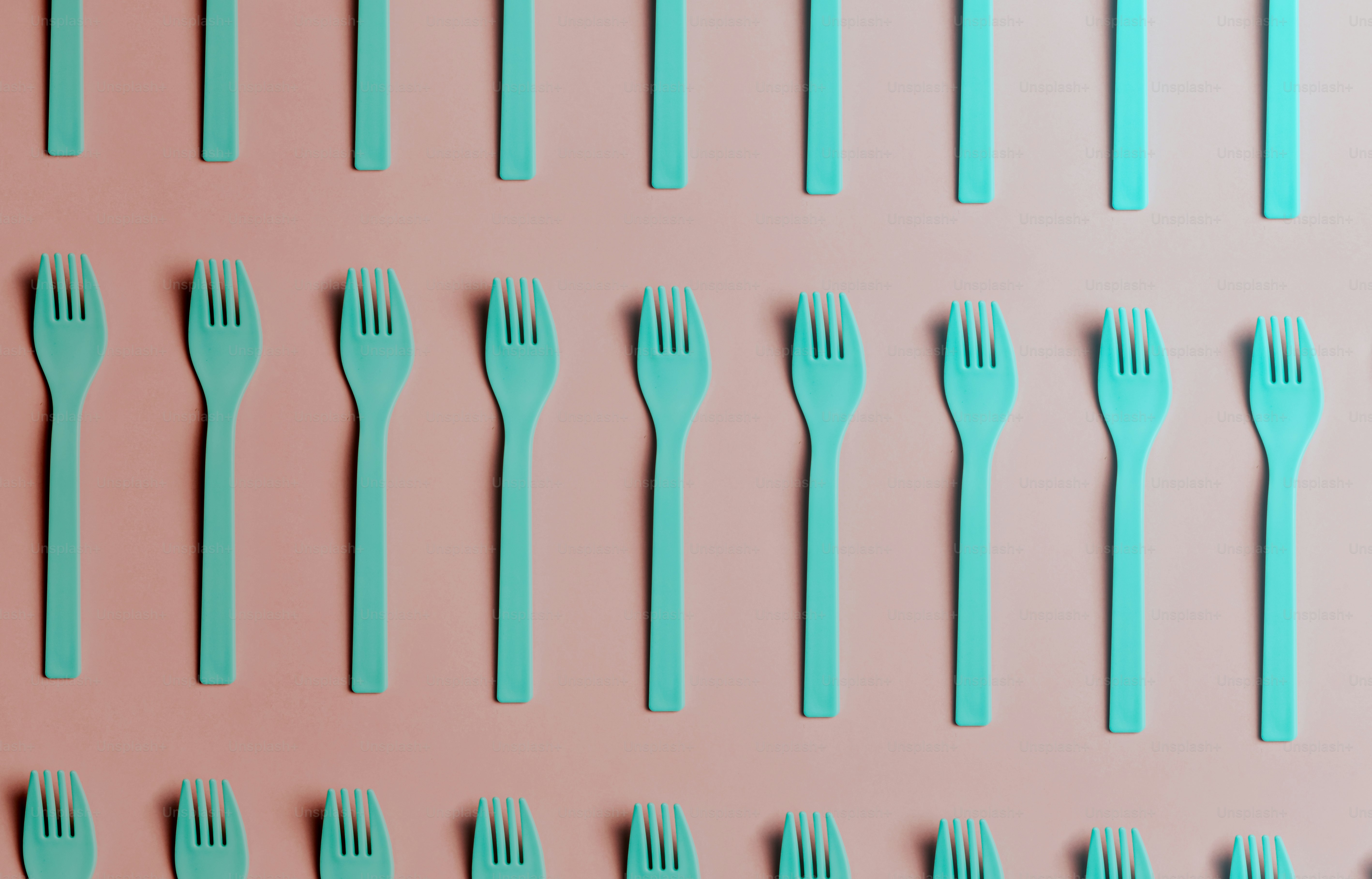 ein Satz blauer Gabeln und Löffel auf rosa Hintergrund