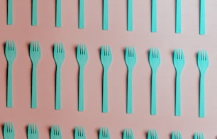 a set of blue forks and spoons on a pink background