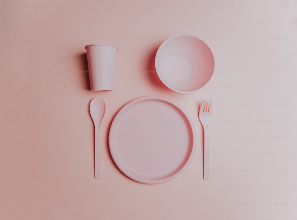 un décor de table rose avec une assiette, une fourchette et une tasse
