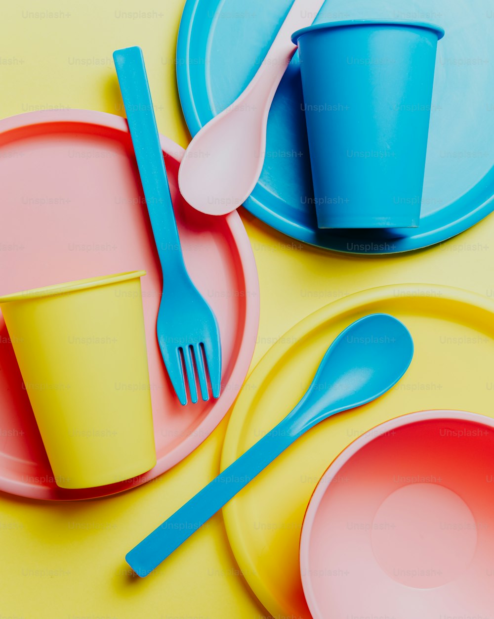 a yellow and blue plate with a cup and a fork