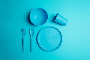 un décor de table bleu avec une assiette, une fourchette et un couteau