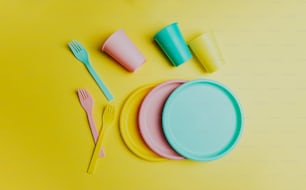 a yellow table topped with plates and cups