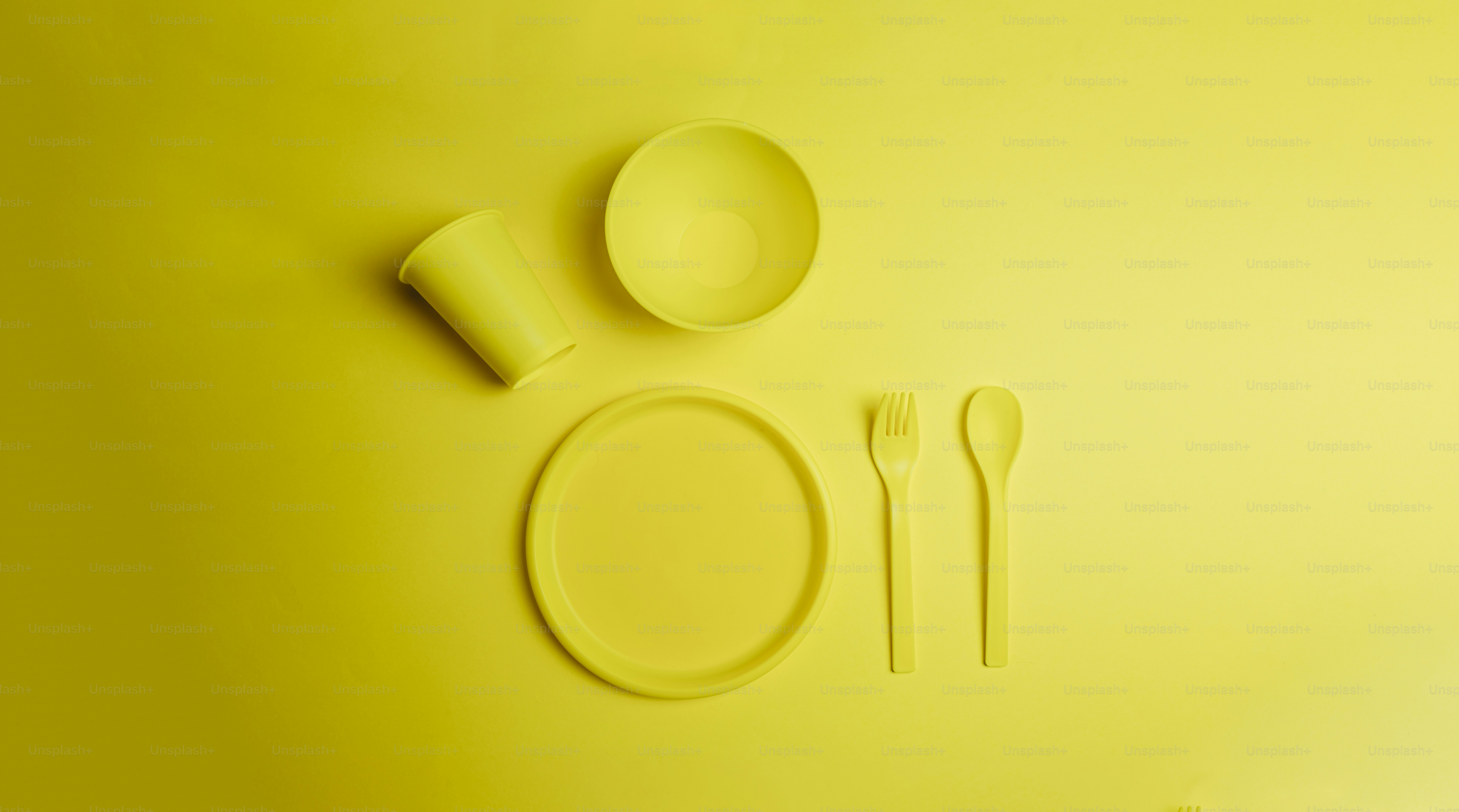 um ajuste de mesa amarelo com um prato, garfo e colher